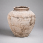 Weathered terracotta jar on gray backdrop